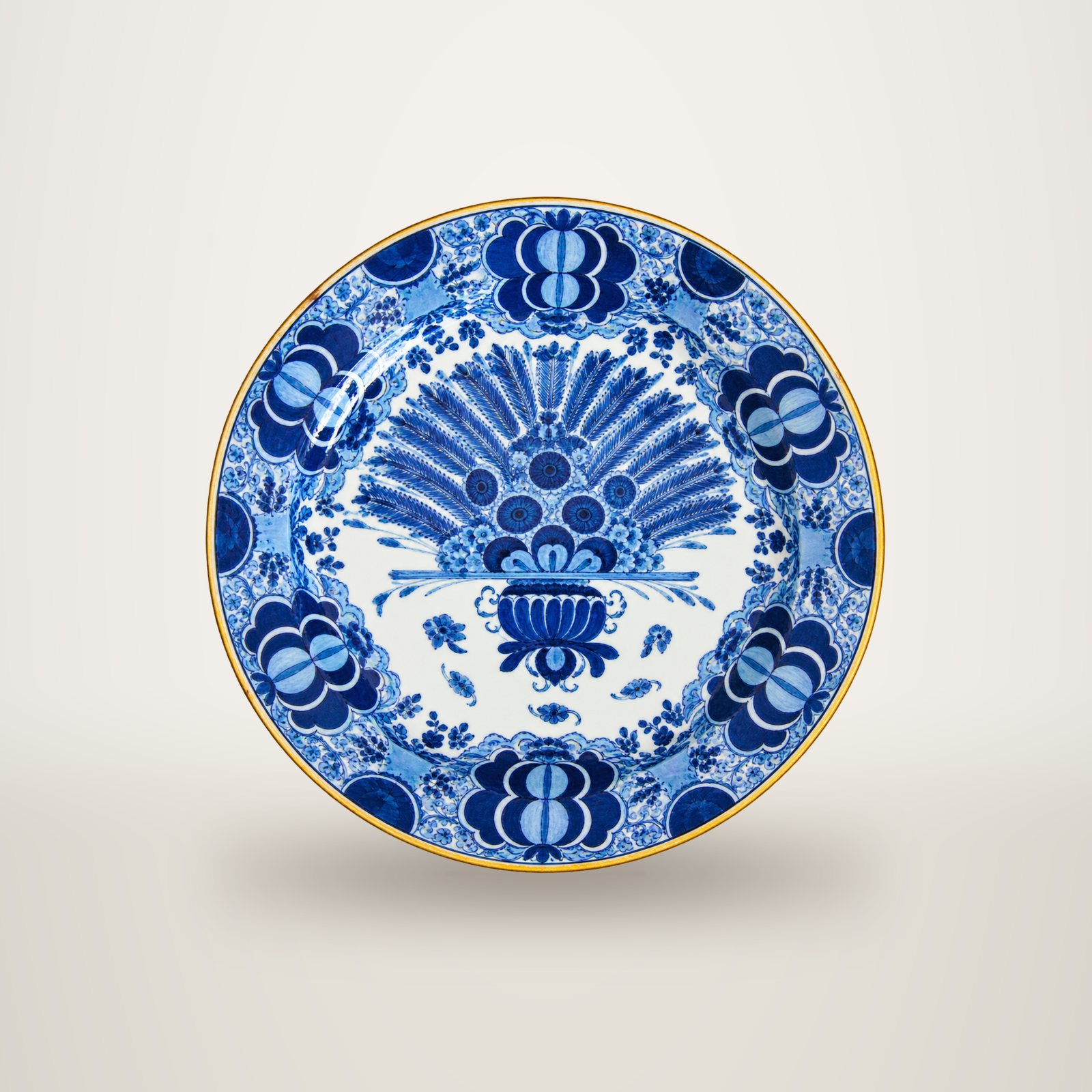 Assiette ancienne en faïence à décor bleu et blanc représentant un paon stylisé avec des motifs floraux sur le bord, photographiée sur fond uni.