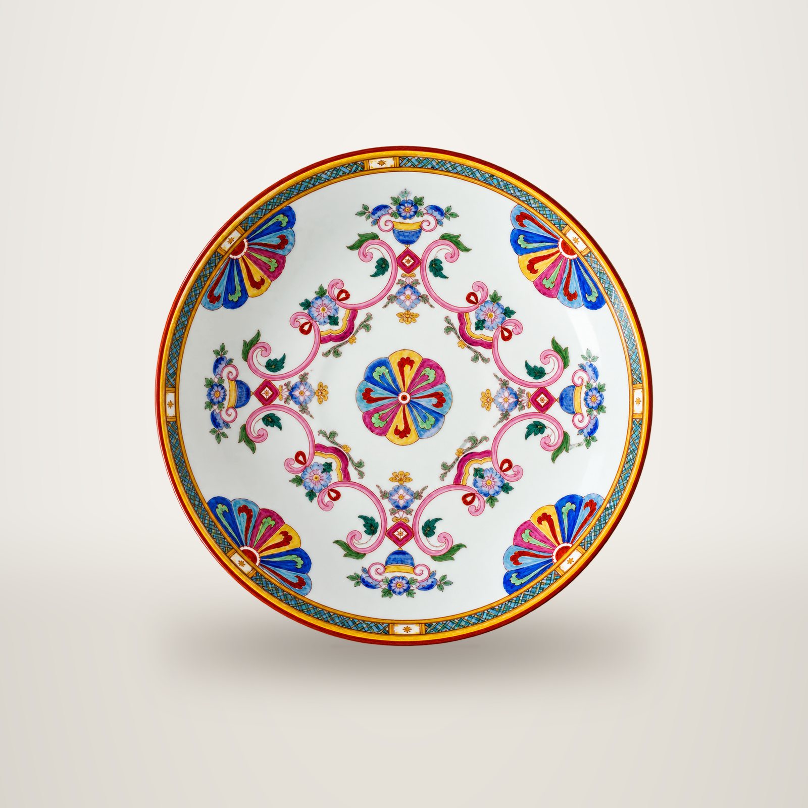 Assiette ancienne en porcelaine blanche ornée de motifs floraux roses, bleus et jaunes, avec un bord orangé, photographiée vue de dessus sur fond blanc.