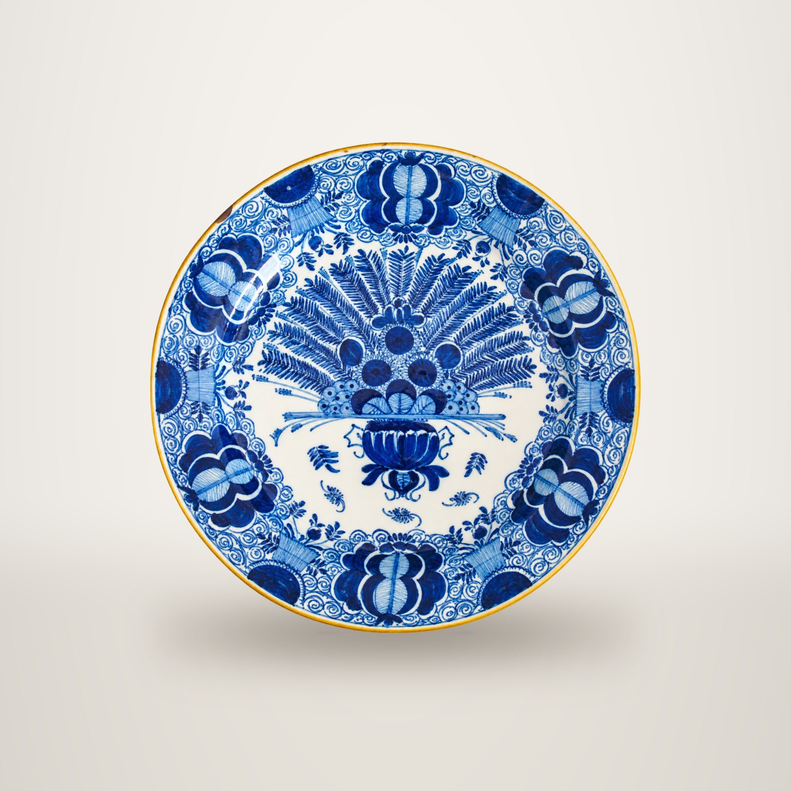 Assiette ancienne en faïence à décor bleu cobalt sur fond blanc, avec un grand bouquet en éventail au centre et des motifs floraux sur le bord.