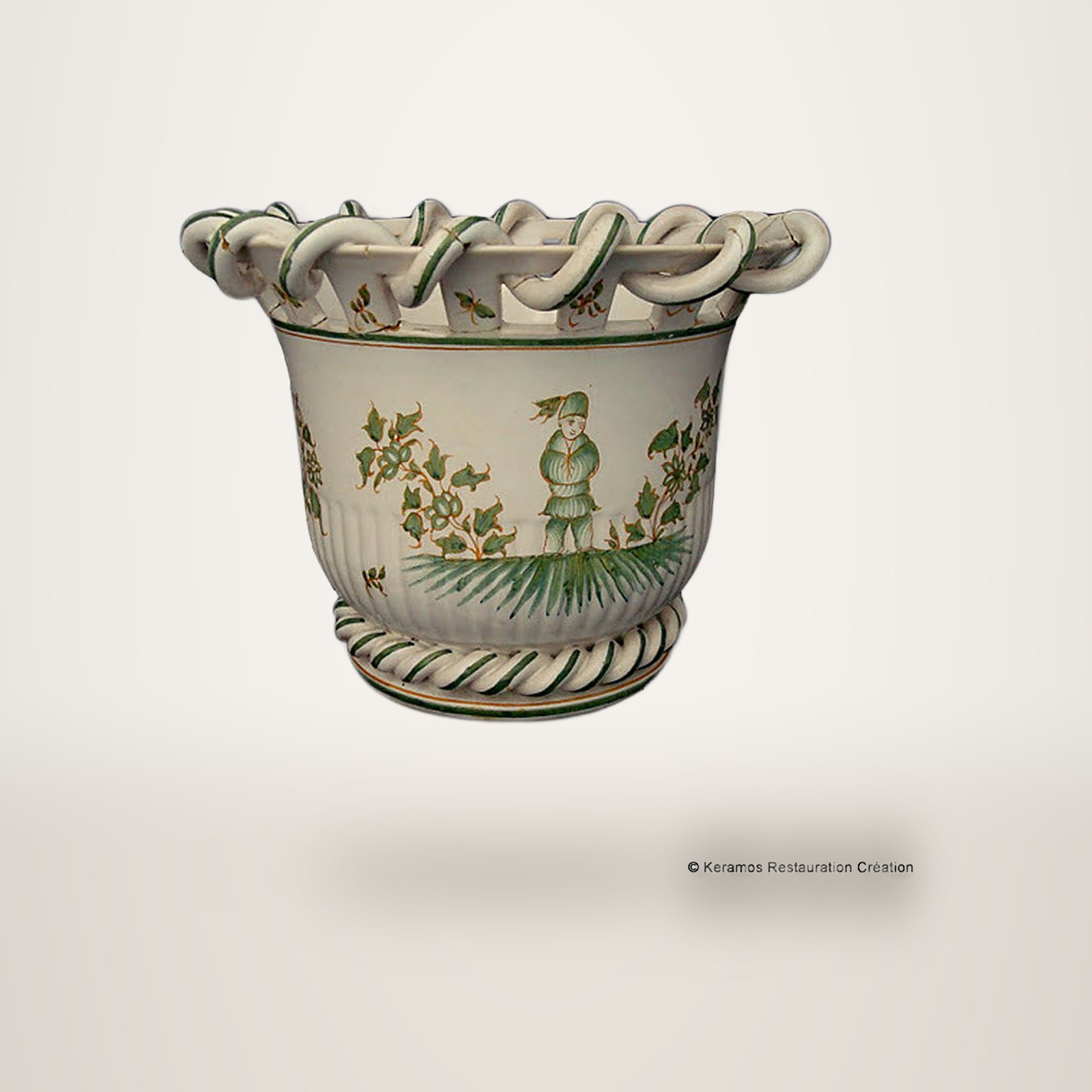 Cache-pot en faïence blanche orné d'un personnage chinois et de fleurs vertes, avec un bord ajouré tressé et un pied en torsade.