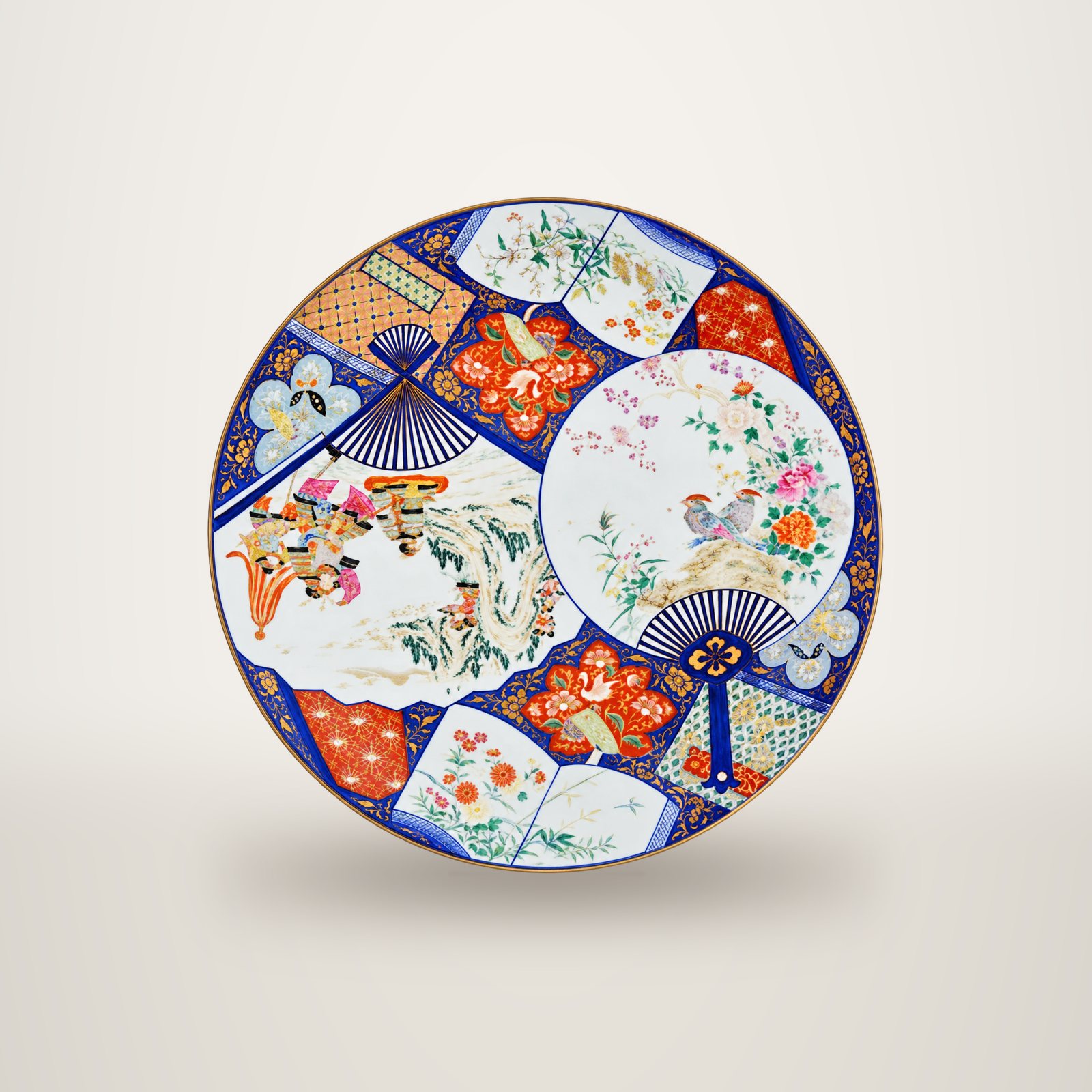 Grand plat en porcelaine japonaise de style Imari, décoré d'éventails, de fleurs, d'oiseaux et de paysages en bleu, rouge et or.