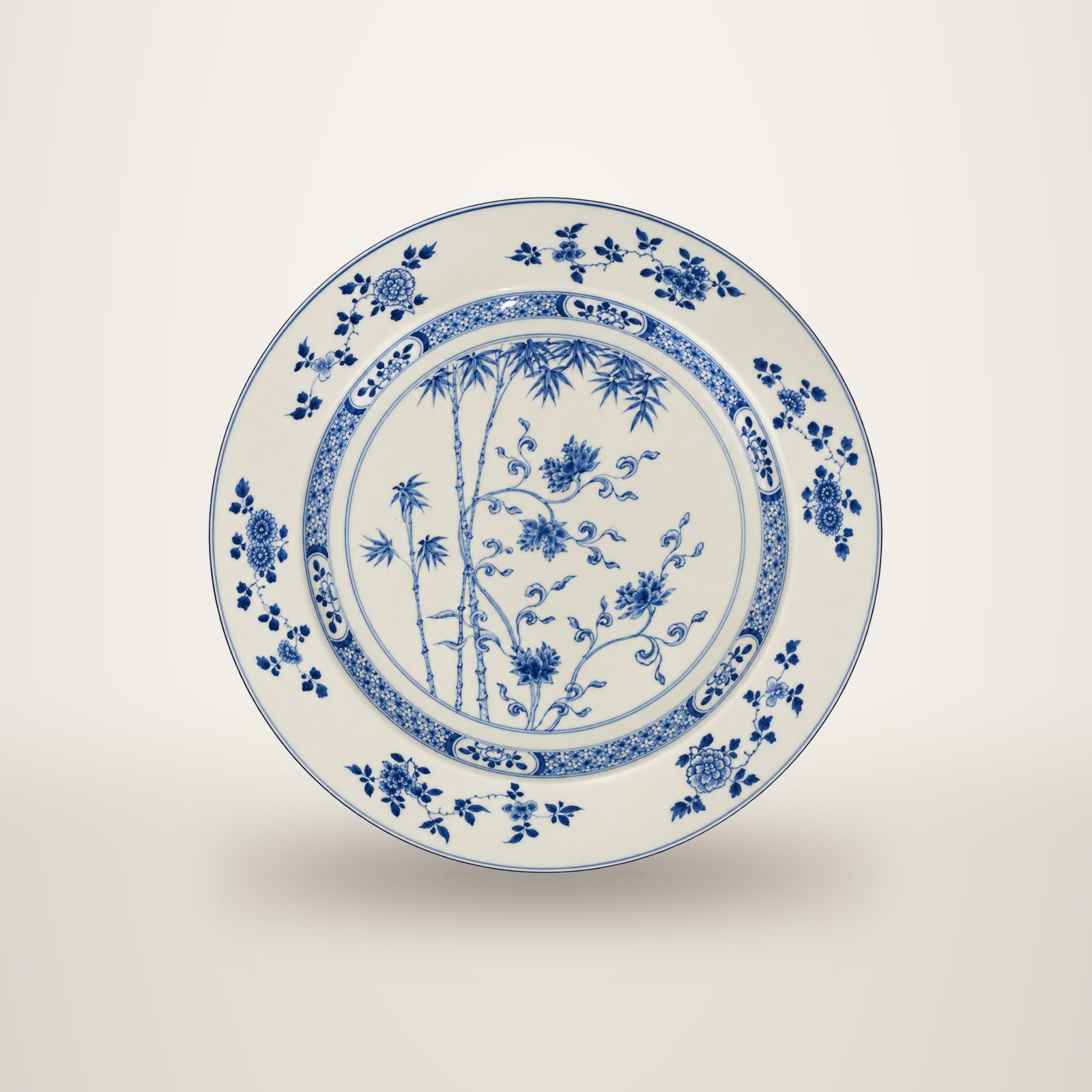 Grand plat rond en porcelaine blanche décoré en bleu de bambous et de fleurs, avec un bord orné de motifs floraux.