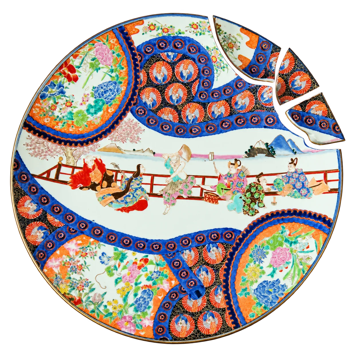 Grand plat en porcelaine aux motifs japonais colorés, bleu, orange et rouge, représentant des personnages près d'une balustrade, avec trois fragments détachés au bord supérieur droit.