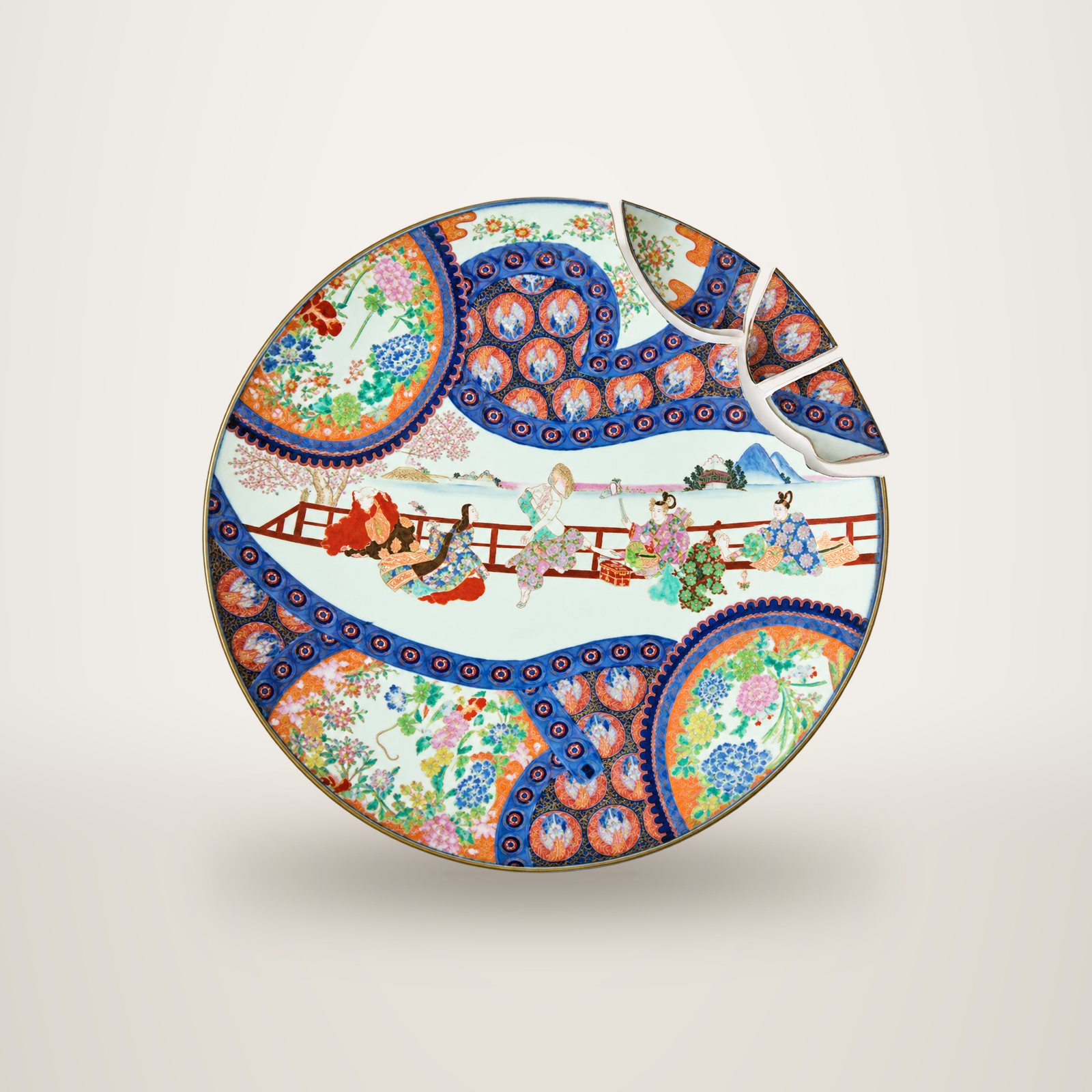 Grand plat rond en porcelaine à décor polychrome de personnages et de fleurs, dont trois morceaux cassés sont séparés en haut à droite.