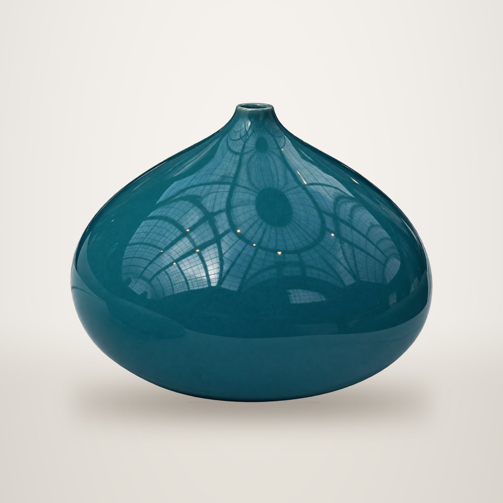 Un vase en céramique émaillée bleu-vert, de forme arrondie et aplatie avec un col étroit, photographié sur fond blanc.