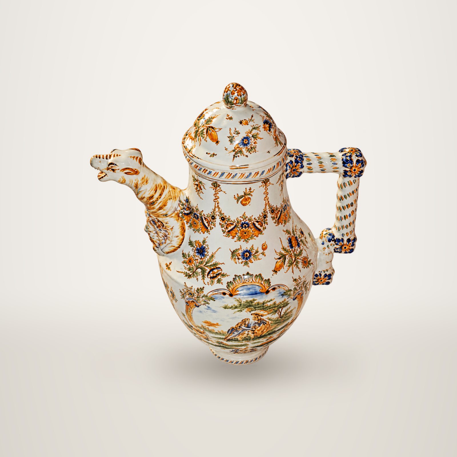 Une verseuse ancienne en faïence blanche à décor floral polychrome, dotée d'un bec en forme de tête d'animal et d'une anse torsadée, photographiée sur fond blanc.
